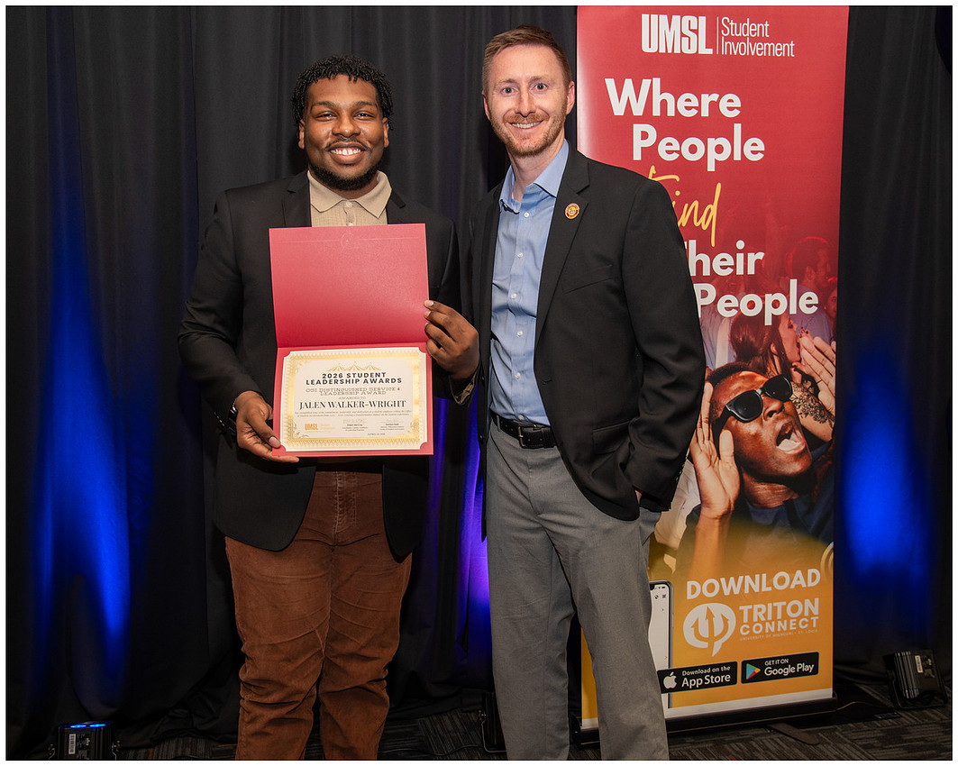 Two people posing with an award at a university event
